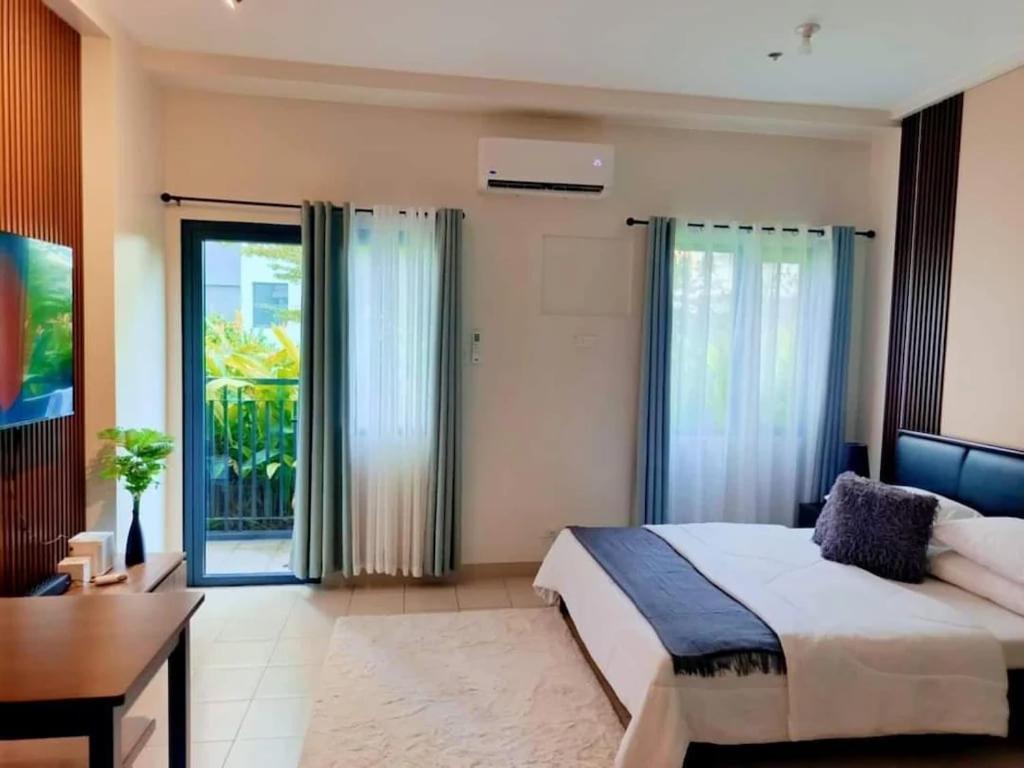 a bedroom with a bed and a desk and windows at Hill Residences by KJA in Manila
