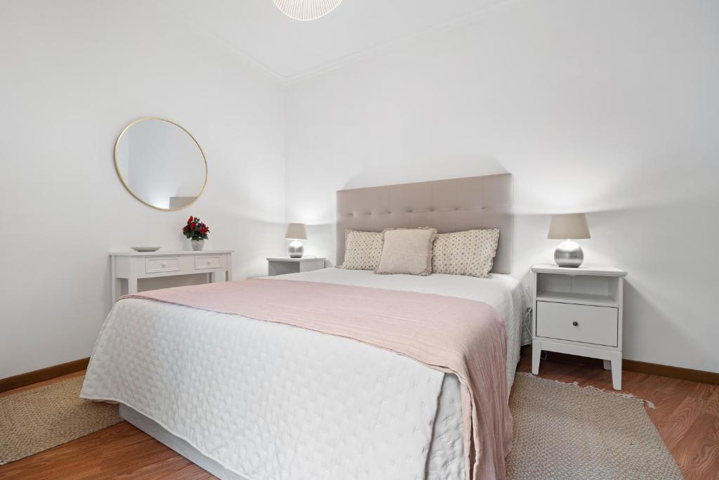 a white bedroom with a large bed and a mirror at Refúgio do Garajau by Atlântica in Caniço