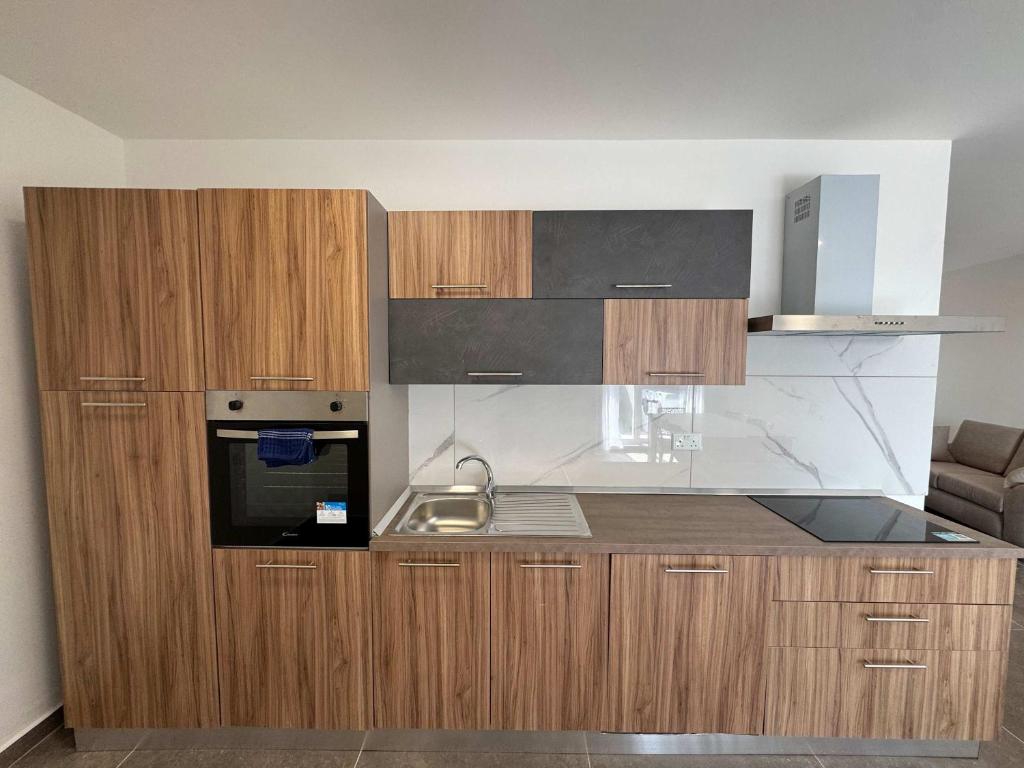 a small kitchen with wooden cabinets and a sink at Serenity Escape 2 Bed with Patio in Taʼ Penza