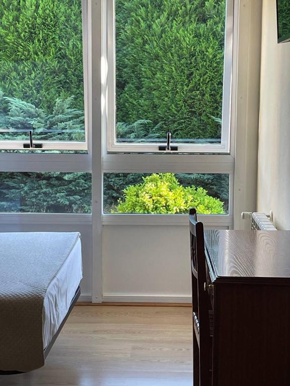 a bedroom with two windows and a bed and a table at Pensión Capital de Galicia in Santiago de Compostela