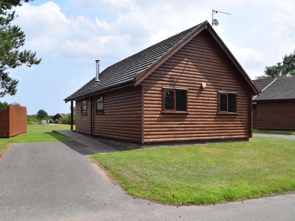 a wooden cabin with a gambrel roof at Willow Plus 2 in Garton