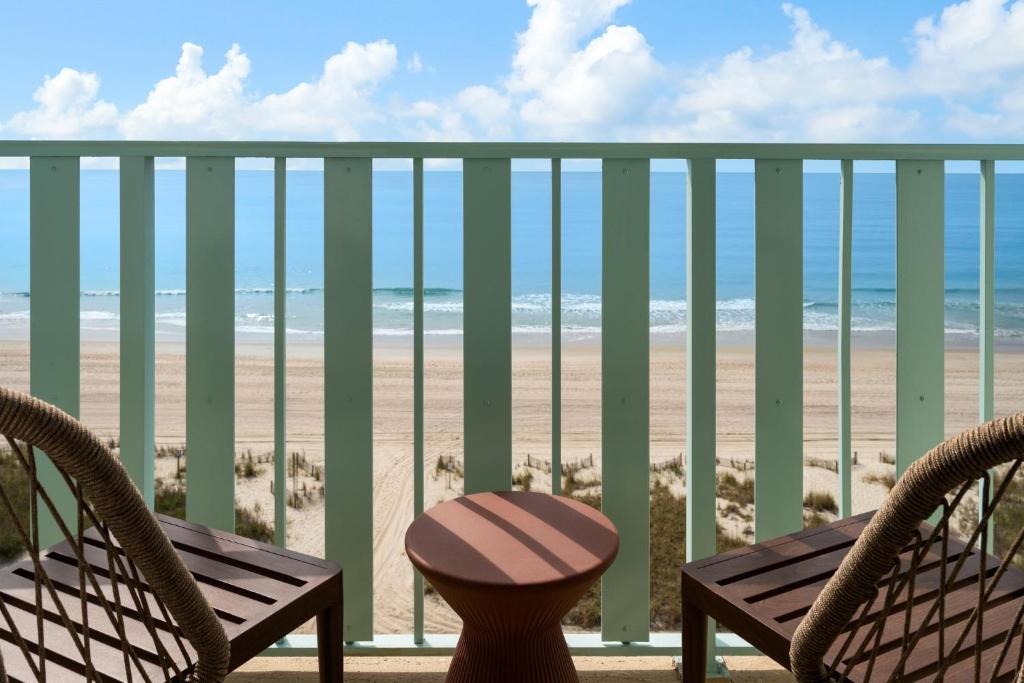 a balcony with a table and chairs and the beach at voco The Shelby - Myrtle Beach by IHG in Myrtle Beach