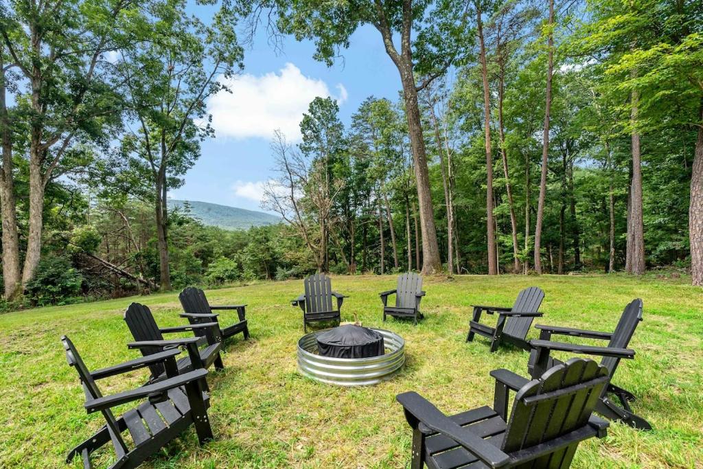 a group of chairs around a fire pit in a field at Bath House Cabin - Hot tub, Sauna, 2 King suites in Berkeley Springs