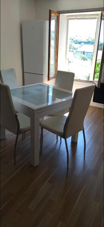 - une table à manger avec 2 chaises et un plateau en verre dans l'établissement Charmant appartement de village, à Roquebrune-sur Argens