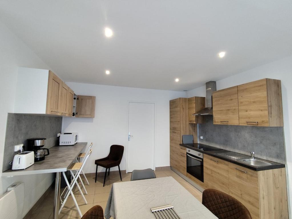 a kitchen with wooden cabinets and a table and chairs at Le sable fin, proche mer, calme et détente in Quend-Plage