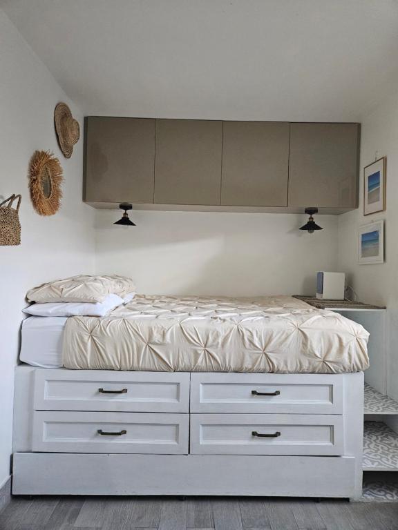 a bedroom with a white bed with drawers and cabinets at Cozy Studio in TCI in Providenciales