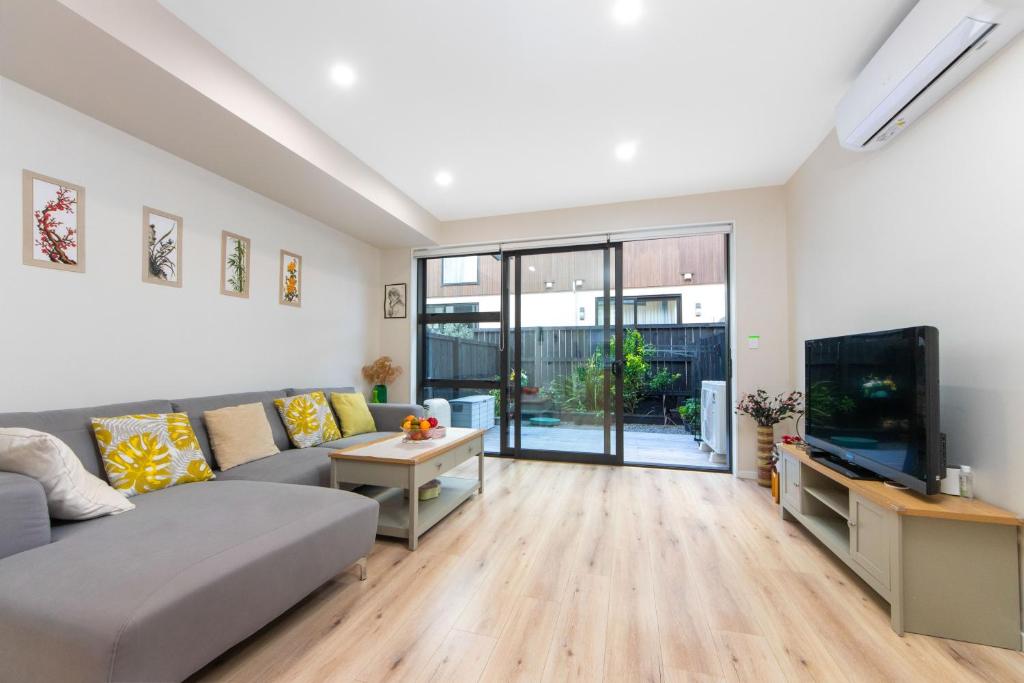 a living room with a couch and a tv at Harborlight--Modern 2 Bedroom Townhouse in Hobsonville in Auckland