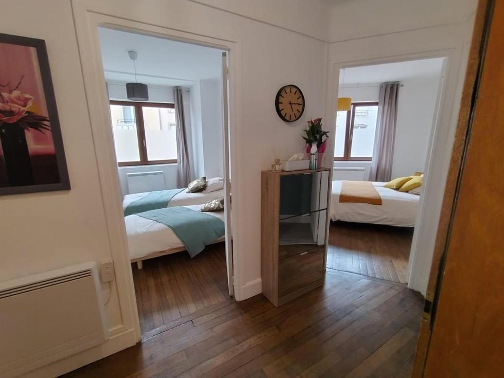 MirecourtにあるAppartement Mirecourt Centreのベッド2台と壁掛け時計が備わる客室です。