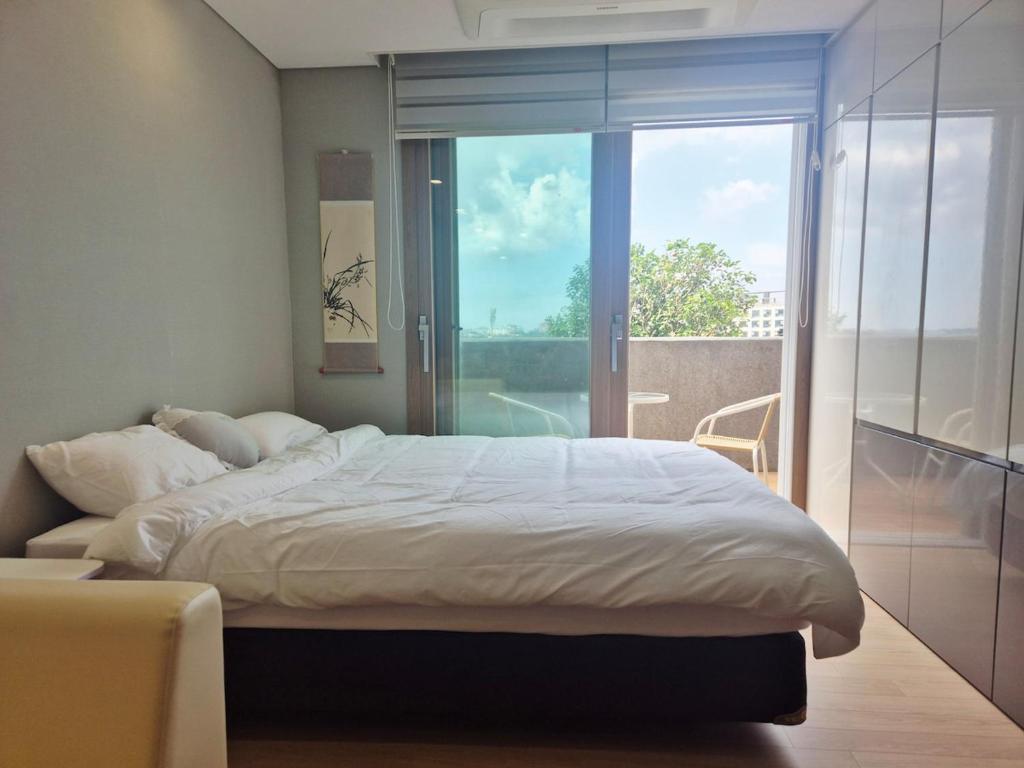 Un dormitorio con una cama grande y una ventana grande. en Relaxing Sunset Healing Ocean TerraceView, en Seogwipo