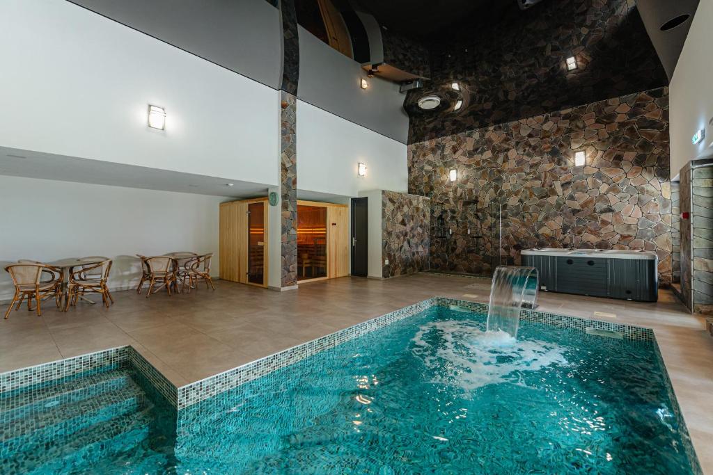a pool with a waterfall in the middle of a room at Apuseni Park Padis in Budureasa