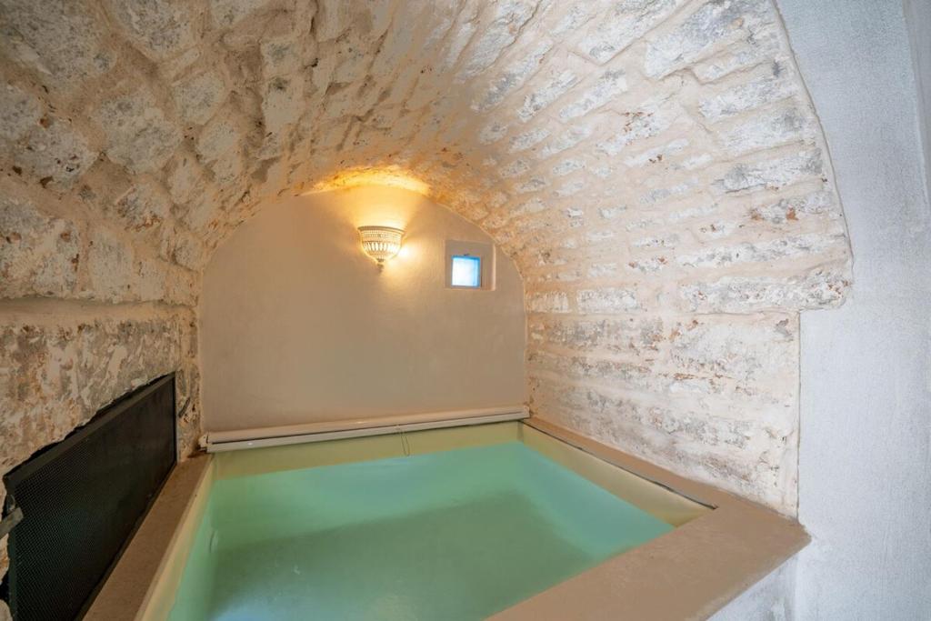 een zwembad in een kamer met een bakstenen muur bij Jacuzzi IV Monte romantic suite with hot tub in Ceglie Messapica