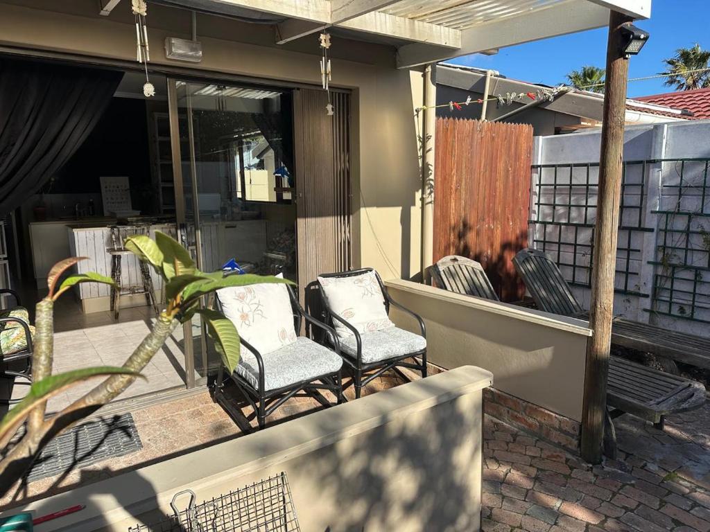 two chairs sitting on the front porch of a house at Winelands Beach Cottage in Gordonʼs Bay