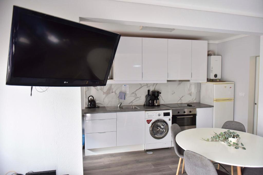 a kitchen with a flat screen tv hanging from a wall at Beira Mar Loft in Aveiro