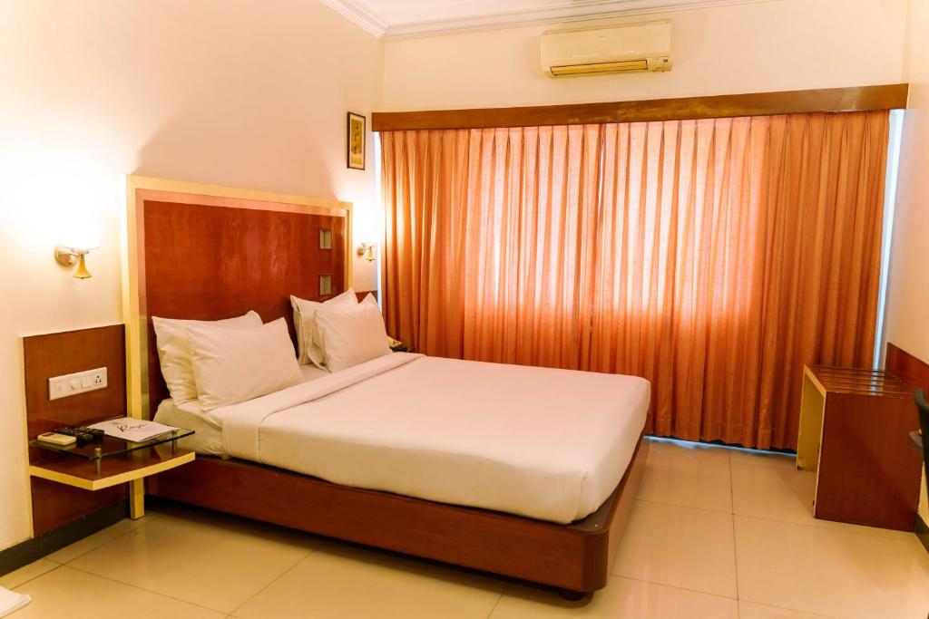 a bedroom with a large bed with a wooden headboard at Bisque Magaji Orchid - Malleshwaram, Near Mantri Square Mall & Majestic in Bangalore