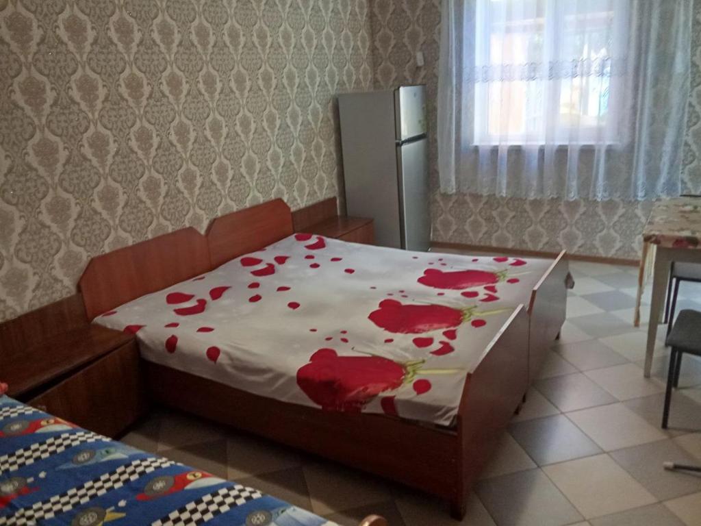 a bedroom with a bed with red flowers on it at Валентина in Kurortne