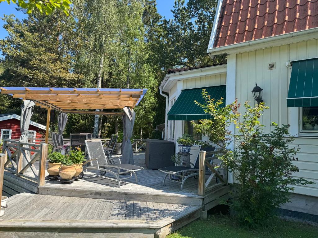 a deck with chairs and a pergola next to a house at Fridfull idyll intill sjö in Uppsala