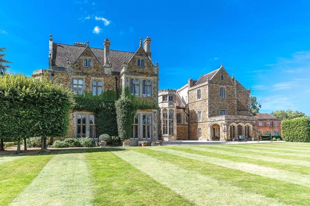 an old mansion with a large lawn in front at Fawsley Hall Hotel in Daventry