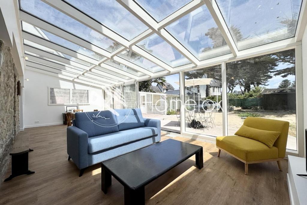 Un invernadero con un sofá, una silla y una mesa. en 10m du sable Déco soignée & bâtiment de caractère, en Saint-Pierre-Quiberon