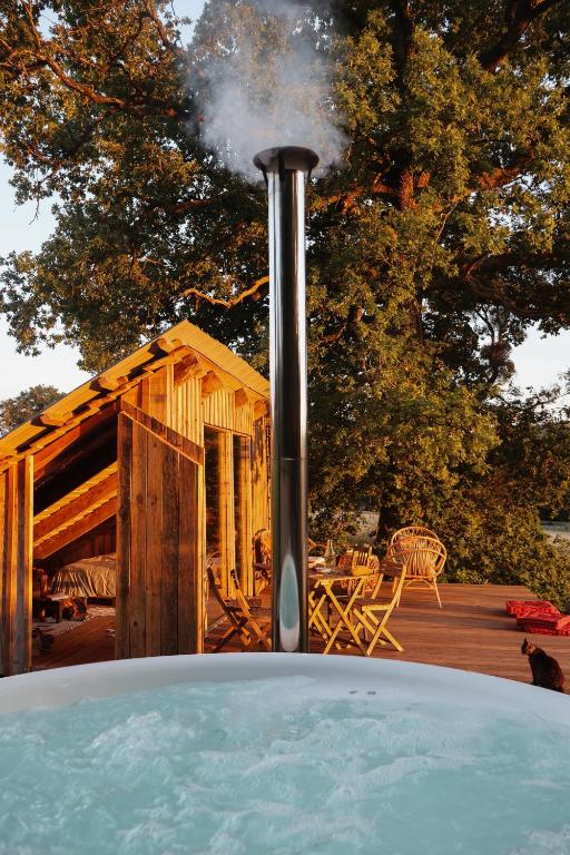 un bain à remous en face d'une maison en bois dans l'établissement La Cabane, à Prailles