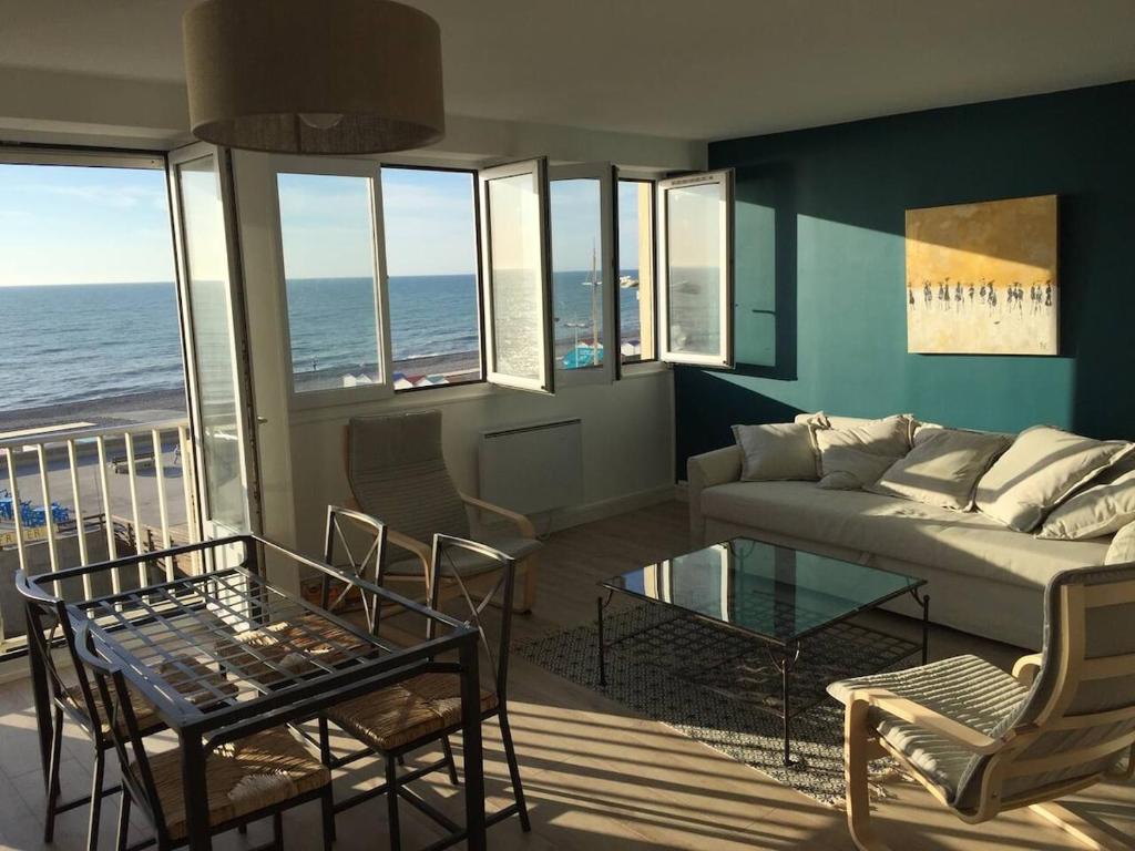een woonkamer met een bank en een tafel bij L'estacade avec sur mer in Le Tréport