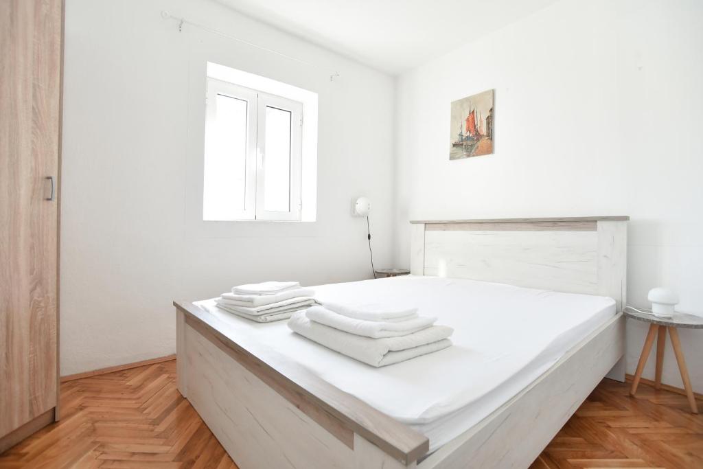 a white bedroom with a bed with towels on it at Stone & Sea in Budva