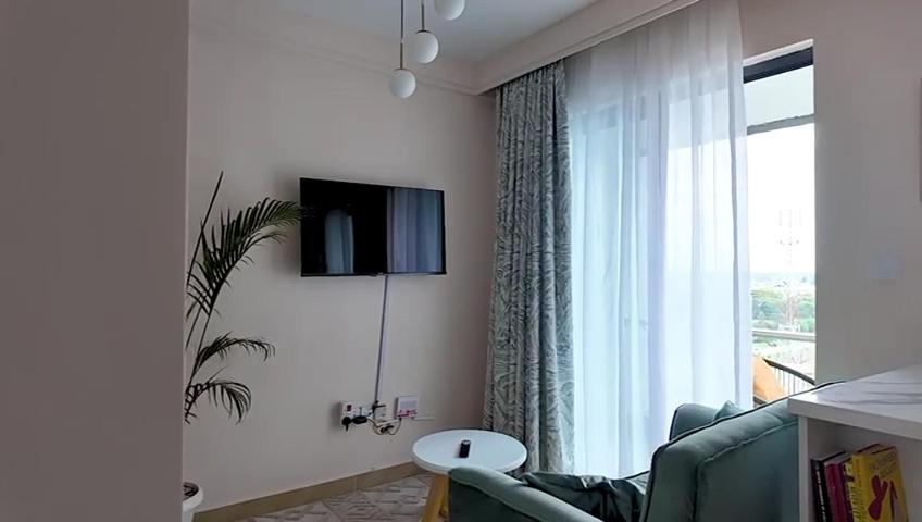 un salon avec un canapé, une télévision et une fenêtre dans l'établissement Uzuri studio apartment, à Nairobi