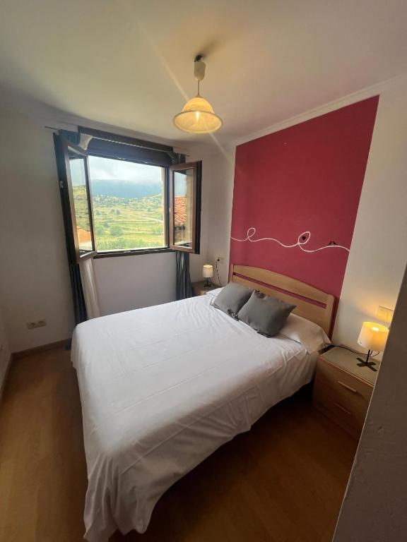 a bedroom with a large bed with a red wall at Casa Senderuela by CARDI Suites in Valdelinares