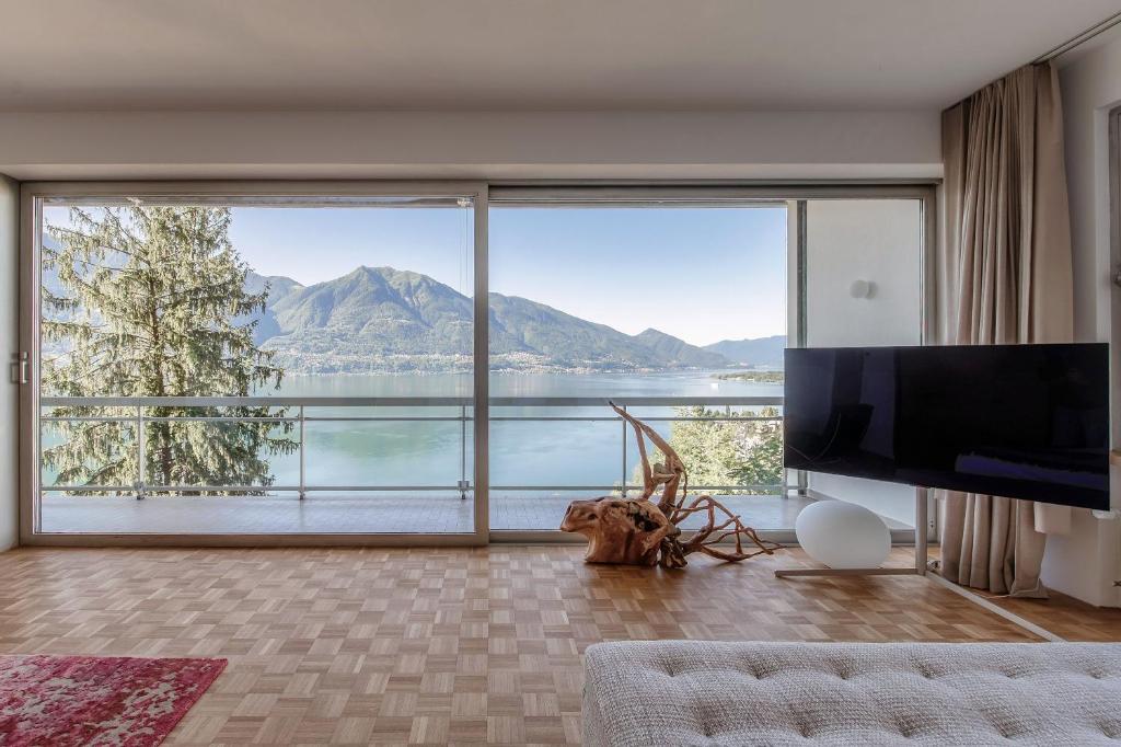 Una sala de estar con una gran vista a una montaña. en Chiar di Luna by Quokka 360 - loft with view of Lake Maggiore, en Minusio