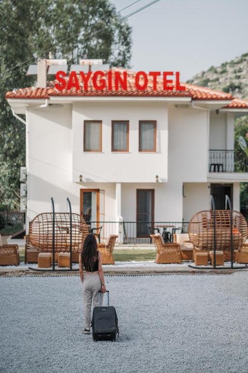 a woman with a suitcase in front of a building at Saygın Otel Selimiye in Selimiye