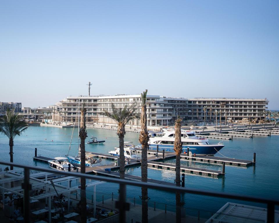 a marina with boats and palm trees and a large building at BirdNest Vacation homes at Marassi marina in El Alamein