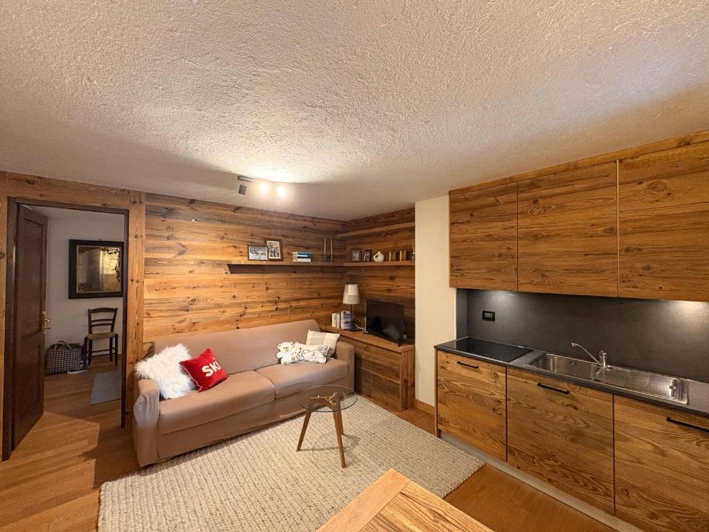 Una sala de estar con un sofá y una cocina. en L'Atelier du Temps - Maison du Glacier, en Entrèves