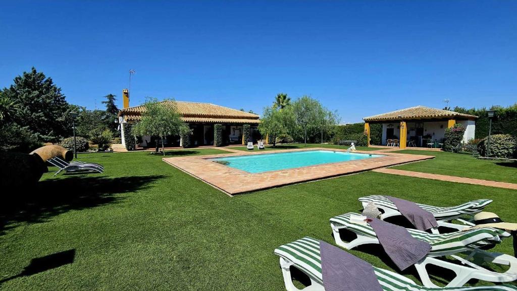 a yard with lounge chairs and a swimming pool at Casa rural Azahares de Marchena in Marchena