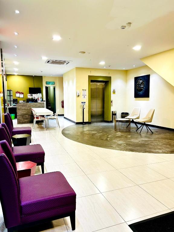a lobby of a hospital with purple chairs and tables at Kino Hotel in Shah Alam