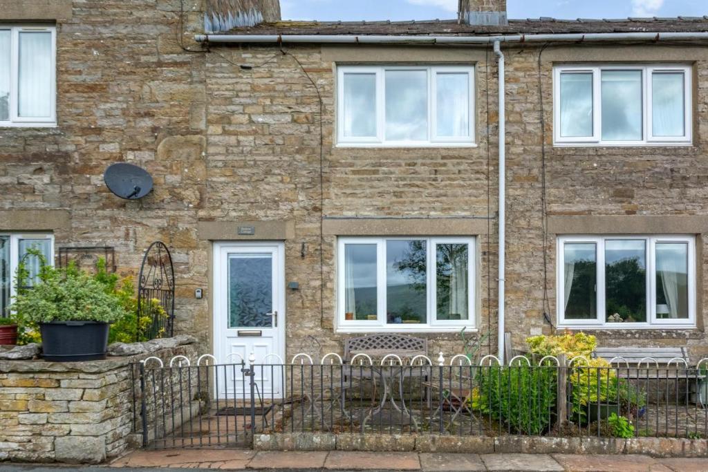 an old brick house with a white door at Butlers Cottage in Hardraw