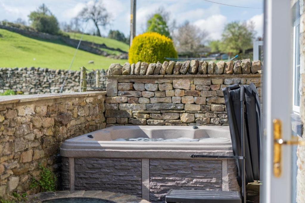 una vasca da bagno accanto a un muro di pietra di Well Cottage - West Burton a West Burton