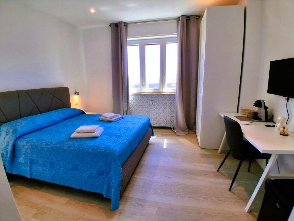 a bedroom with a blue bed and a desk and a window at Virgy White rooms in Bari