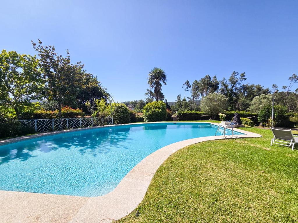 a swimming pool in a yard with two chairs at Casa das Quintas - Refúgio Rural com Piscina in Além da Ribeira