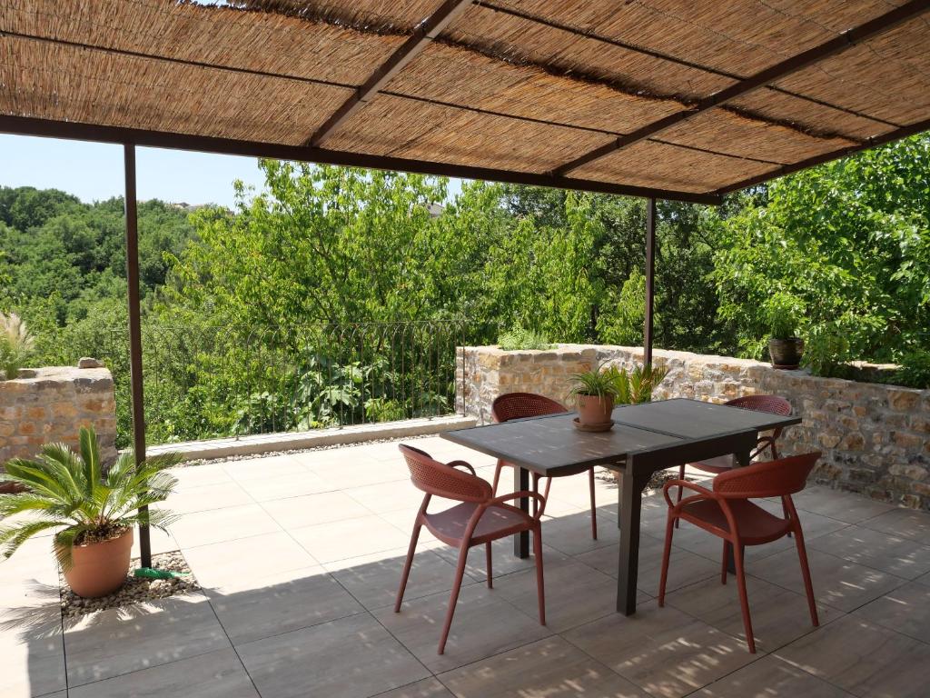 a patio with a table and chairs under a pergola at Le Gîte des Missols in Saint-Étienne-de-Fontbellon