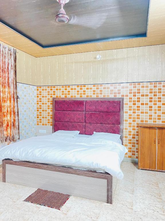 a bed with a purple headboard in a room at Hotel Tara Palace By MIDTOWN in Katra