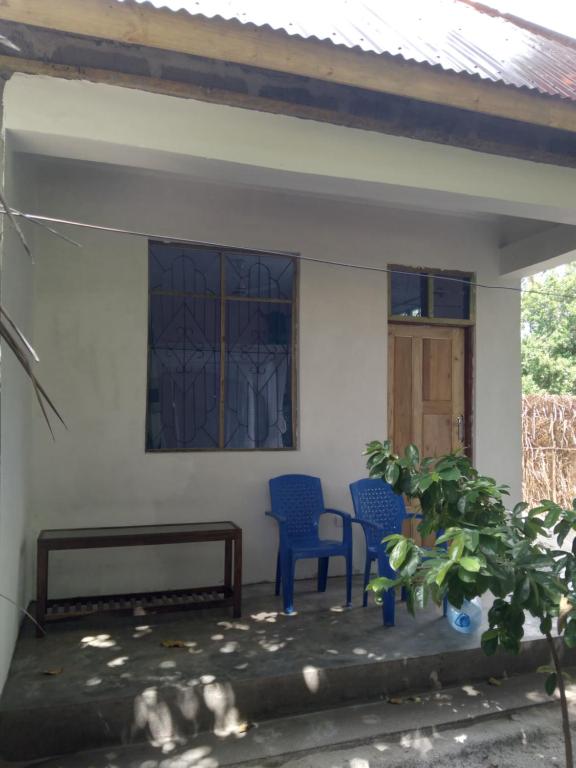 a house with two blue chairs and a window at Momi Home Stay in Utende