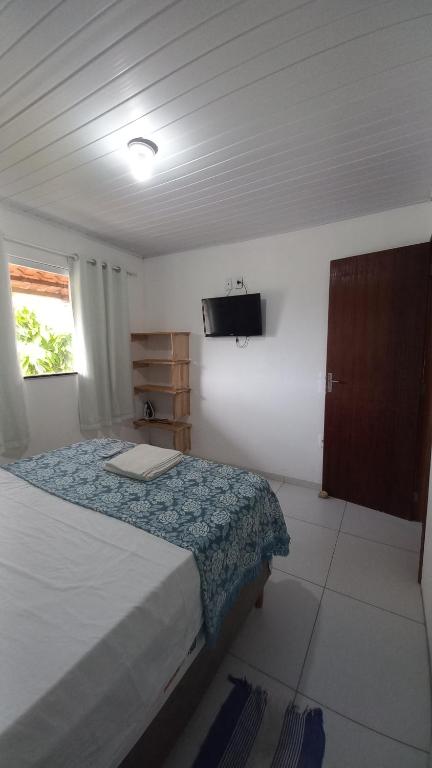 a bedroom with a bed and a tv on the wall at Casa do Carlos - Boipeba in Ilha de Boipeba