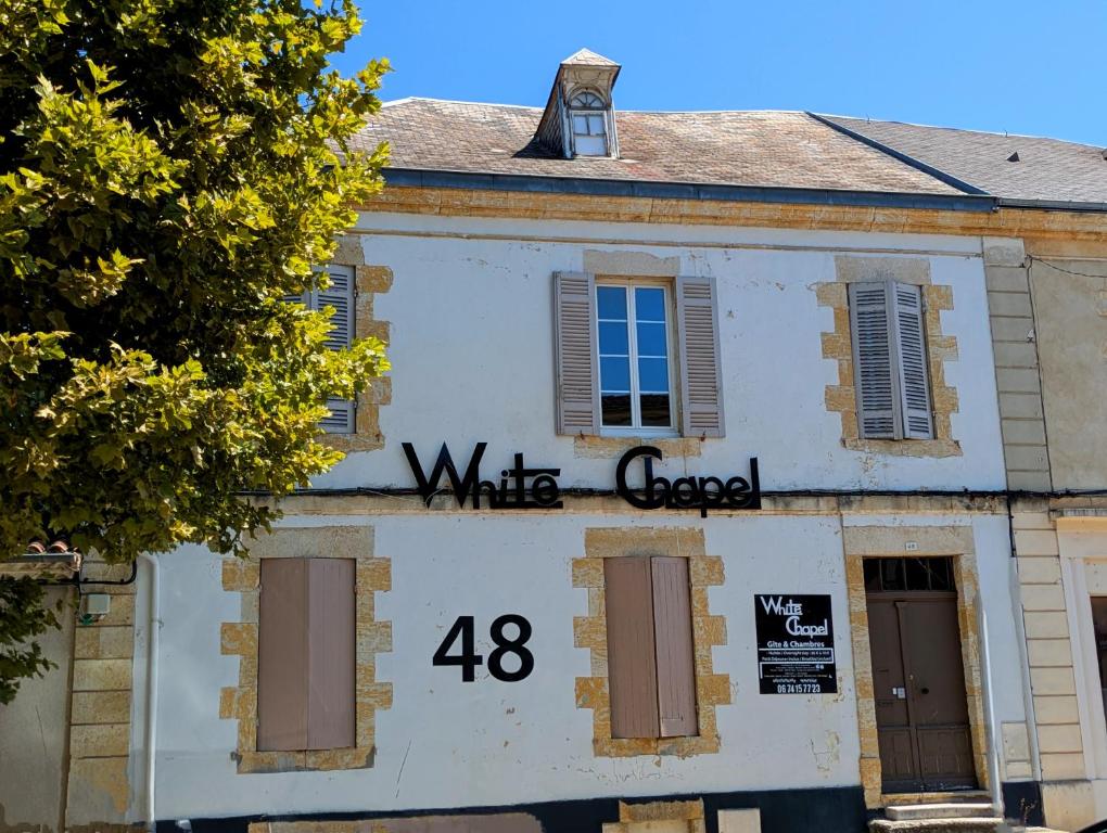 un bâtiment blanc avec les mots « white gap » dessus dans l'établissement White Chapel, à Condom