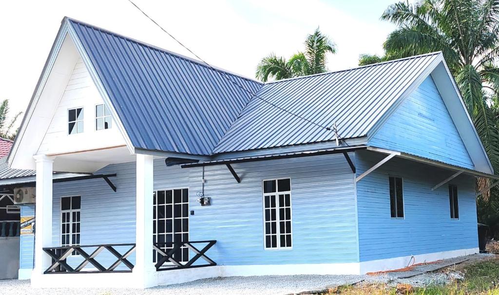 una casa azul y blanca con techo de metal en Amyza Homestay 3Bilik, en Semerah