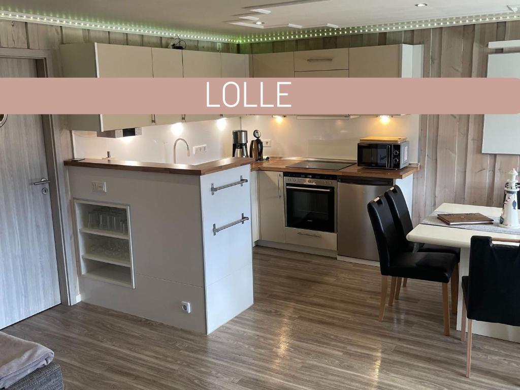 a kitchen with white cabinets and a table and a counter top at Dreibogen Ferienwohnung Lolle in Glücksburg
