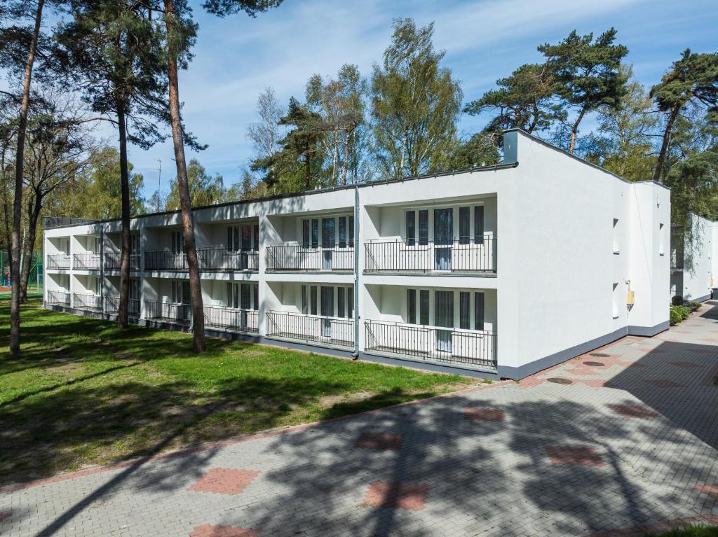 an exterior view of a white building with trees at DIUNA Łeba in Łeba