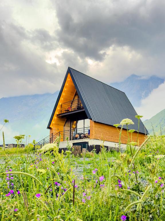 a house with a black roof in a field of flowers at Chill inn kazbegi in Kazbegi