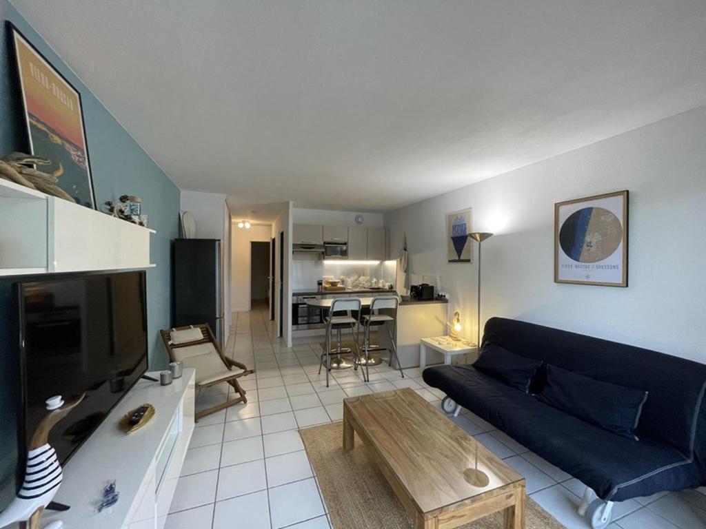 un salon avec un canapé bleu et une table dans l'établissement Agréable T2 avec piscine et animaux admis - FR-1-379-182, à Soustons