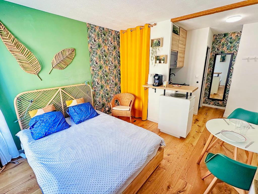 Cet appartement comprend une chambre avec un lit doté d'oreillers bleus et une cuisine. dans l'établissement 07-1 - Cozy & élégant - TV sat&VOD, à Villeurbanne