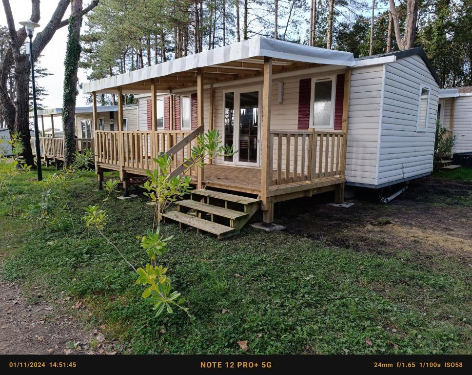 a tiny house with a porch and stairs in a yard at Mobil home 6 personnes Mer et Pins in Piriac-sur-Mer
