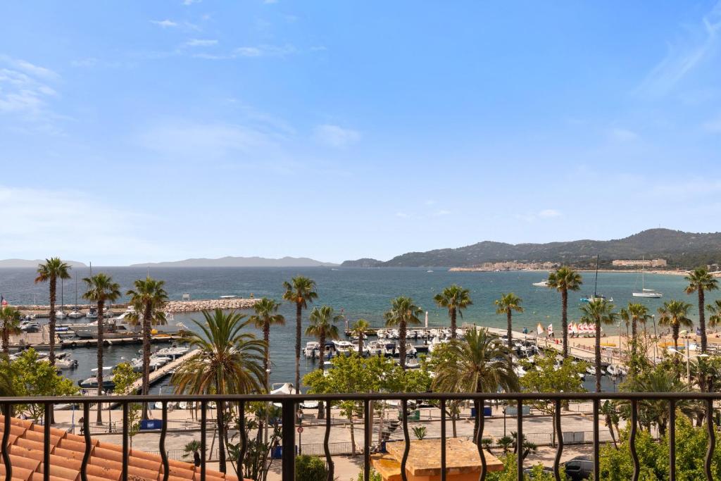 Una vista de una playa con palmeras y el océano. en Constance d'Azur - Climatisé vue mer, en Le Lavandou